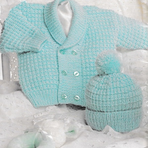 Könnte beinhalten: Ein hellblauer gestrickter Baby-Cardigan mit doppeltem Knopfschloss und vier Knöpfen. Der Cardigan hat einen breiten Kragen und wird mit einer passenden hellblauen Strickmütze mit Bommel kombiniert.