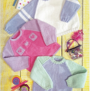 May include: Three knitted sweaters in different colors and patterns. The first sweater is white with blue sleeves and white stripes. The second sweater is pink with purple sleeves and a heart design. The third sweater is purple with green sleeves.