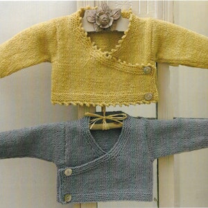 May include: Two knitted baby sweaters, one yellow and one gray, with a wrap-around style and button closures. The sweaters are hanging on a wooden hanger.