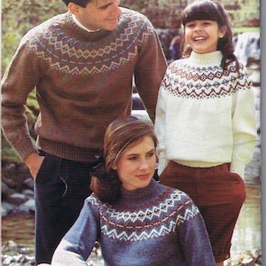 Puede incluir: Una familia lleva suéteres de punto a juego con un patrón escandinavo tradicional. Los suéteres son de color marrón, blanco y azul con cuello alto.