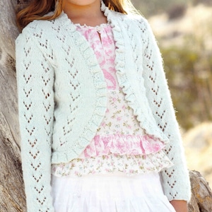 Könnte beinhalten: Eine hellgrüne Häkeljacke mit Rüschenbesatz. Die Jacke ist vorne offen und hat ein zartes Spitzenmuster.