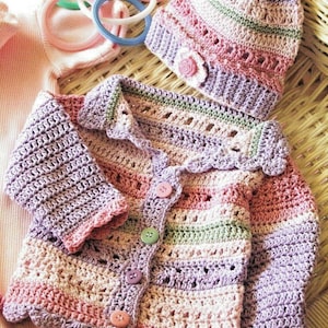 May include: A pastel-coloured, handmade crochet baby set, comprising a cardigan and matching hat. The cardigan has a scalloped edge, button closure, and striped design. The hat features a flower. The set is made of soft yarn.
