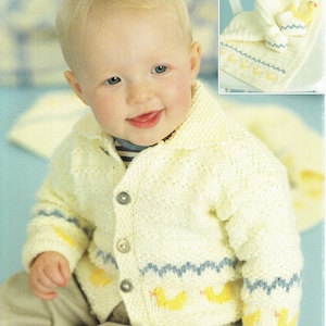 Op de afbeelding: Een baby draagt een wit gebreid vest met een blauw en geel patroon. Het vest heeft een knoopsluiting en heeft een klein geel eendje ontwerp. De baby zit op een blauwe ondergrond.