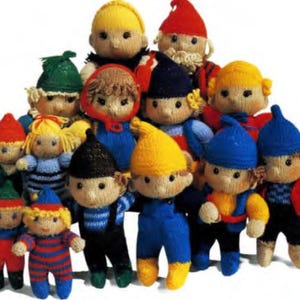 May include: A group of knitted dolls in various colors and styles. The dolls are all wearing different outfits and have different facial expressions. Some of the dolls are wearing hats, while others are wearing scarves. The dolls are all standing together in a group.