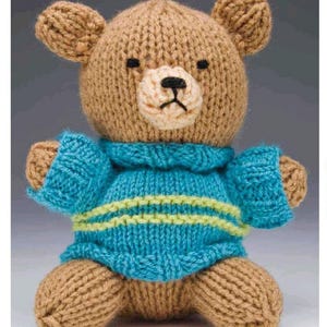 May include: A brown knitted teddy bear wearing a blue and green striped sweater. The bear has a stitched-on nose and black eyes.