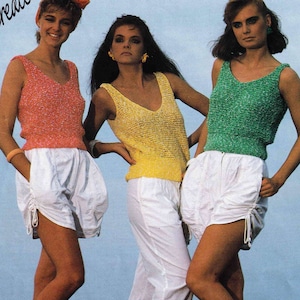 May include: Three women wearing sleeveless tops and white shorts. The tops are knitted and have a textured look. The first top is pink, the second is yellow, and the third is green.