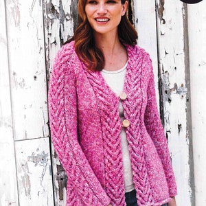 May include: A pink knitted cardigan with a cable knit pattern and wooden buttons. The cardigan has a V-neck and long sleeves.