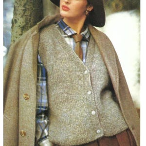Peut inclure: Une femme portant un gilet en tricot marron avec des boutons, une chemise à carreaux bleu et blanc, une cravate marron et un chapeau marron. Elle est debout à côté d'un arbre.