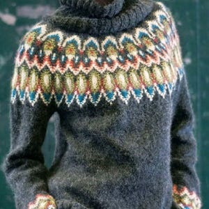 May include: A dark gray turtleneck sweater with a colorful patterned yoke and cuffs. The pattern includes white, blue, red, and green geometric shapes. The sweater is made of a soft, textured material.