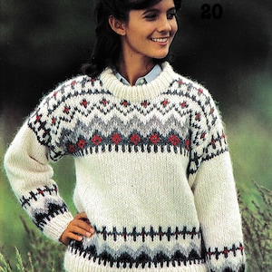 Puede incluir: Jersey de punto color crema con un patrón geométrico en rojo, gris y negro. El jersey tiene cuello redondo y mangas largas. El número "20" está en la esquina superior derecha.