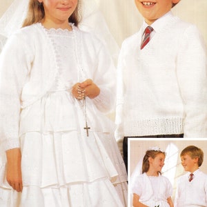 May include: Two children dressed in white for a special occasion. The girl is wearing a white dress with a lace trim and a white cardigan. She is holding a rosary. The boy is wearing a white sweater with a V-neck and a red and white striped tie.