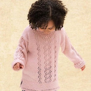 Może przedstawiać: Różowy sweter dzianinowy z delikatnym wzorem koronkowym. Sweter ma okrągły dekolt i długie rękawy.