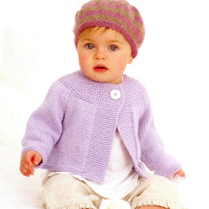 May include: A baby wearing a lavender knitted cardigan with a single button closure and a pink and brown striped knitted hat.