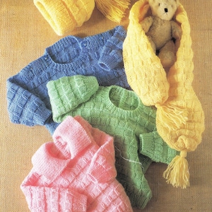 May include: A collection of hand-knitted baby clothes in various colors. The image features a yellow hat with a tassel, a blue sweater, a green sweater, a pink sweater, and a yellow scarf with a teddy bear inside.
