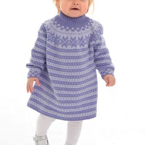 Può includere: Un vestito di maglia viola e bianco con un motivo a fiocco di neve. Il vestito ha maniche lunghe e un collo alto.
