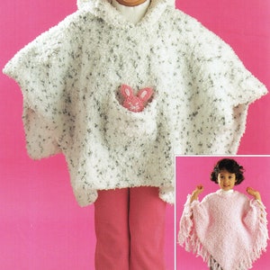 May include: A white hooded poncho with a pink bunny pocket. The poncho is made of a fuzzy yarn and has a fringed edge. A second image shows a pink version of the poncho.