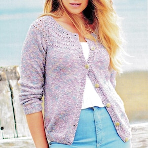 May include: A light purple knit cardigan with a round neckline and button closure. The cardigan is worn over a white top and paired with light blue jeans. The buttons are a light brown color.