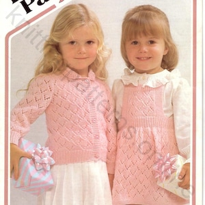 May include: A knitting pattern for a pink cardigan and dress for girls, ages 18 to 22 inches. The pattern is called "Darling 4 ply" and is a Wendy design. The pattern number is P474.