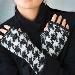 Può includere: Guanti senza dita a maglia con motivo pied-de-poule bianco e nero. I guanti hanno un design classico. Il motivo bianco e nero è un motivo ripetuto. I guanti sono indossati sopra una giacca nera.