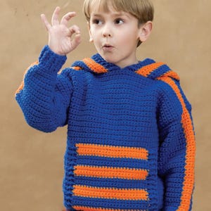 Peut inclure: Un sweat à capuche bleu crocheté avec des rayures orange sur les manches et le devant. La capuche et les bordures des manches sont également orange. Le sweat est fait à la main et convient aux enfants.