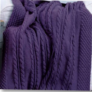 May include: A purple knitted throw blanket with a cable knit pattern.
