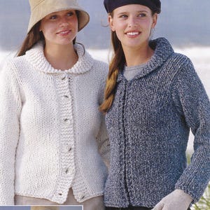 May include: Two women wearing knitted cardigans. The woman on the left is wearing a white cardigan with a collar and buttons. The woman on the right is wearing a blue and white cardigan with a collar and buttons.
