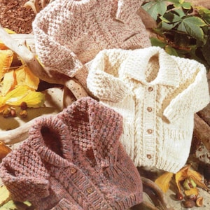 May include: Three knitted cardigans in different colours and patterns. The cardigan on the left is brown with a cable knit pattern, the middle cardigan is white with a cable knit pattern, and the cardigan on the right is cream with a textured knit pattern.