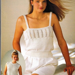 May include: A white crocheted sleeveless top with a delicate lace pattern. The top has a square neckline and a fitted bodice. The model is wearing white shorts.