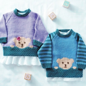 May include: Two knitted baby sweaters with teddy bear appliques. One sweater is purple with a green teddy bear and the other is blue with green and white stripes and a brown teddy bear.