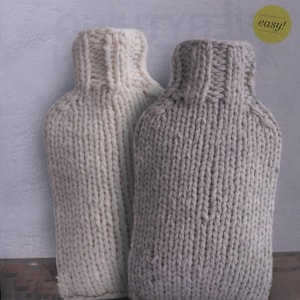 May include: Two knitted hot water bottle covers, one white and one gray. The covers are made with a simple knit stitch and have a ribbed collar.