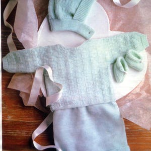 May include: A light blue knitted baby outfit set, including a hat, sweater, and booties.