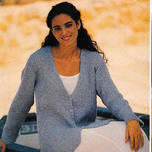 May include: A light blue knitted cardigan with a V-neck and button closure. The cardigan is made of a soft, textured yarn and has long sleeves.