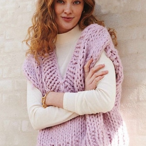 Może przedstawiać: Beżowy, dzianinowy bezrękawnik z dekoltem w kształcie litery V. Bezrękawnik wykonany jest z grubego włókna i ma luźny krój.