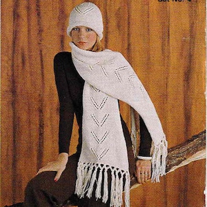 May include: A white knitted hat and scarf set with a geometric pattern. The scarf has fringe on the bottom and the hat has a small brim.