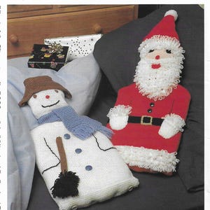 May include: A knitted snowman and Santa Claus hot water bottle set. The snowman is white with a brown hat, blue scarf, and black broom. Santa is red with a white beard and black belt.