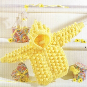 May include: A yellow knitted baby cardigan with a hood and button fastening. The cardigan has a textured, bobbly stitch pattern.