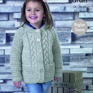 May include: A light gray cable knit cardigan with a button closure and a pocket on the front. The cardigan is made for a child and has a raglan sleeve. The text "aran" and "Raglan Sleeve" is visible on the image. The text "56 - 76 cm, 22 - 30 in" is also visible.