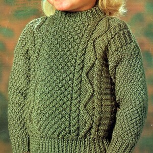 May include: A green knitted sweater with a cable knit pattern. The sweater has a high neck and long sleeves.