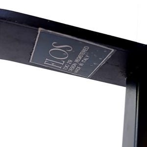 May include: A black metal frame with a white label that reads "FLOS TOTO 219 DESIGN REGISTERED MADE IN ITALY".