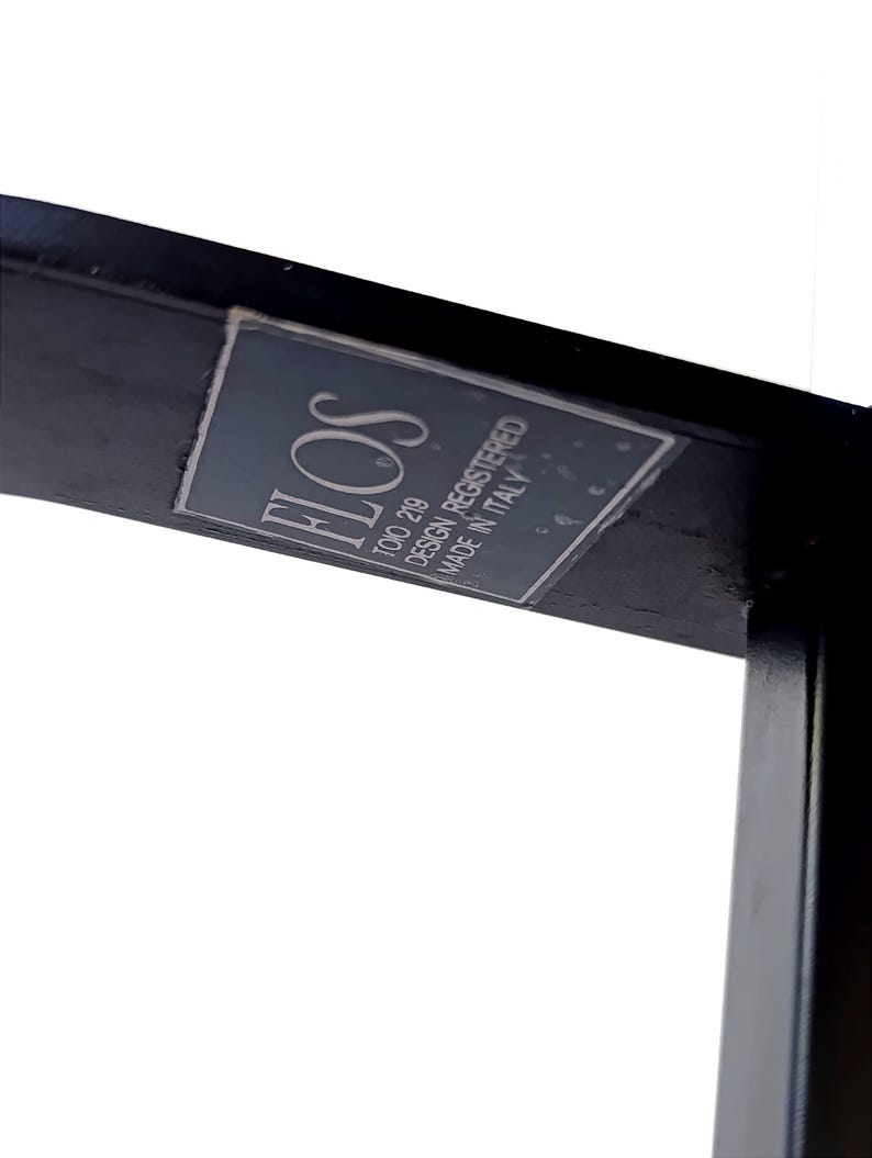May include: A black metal frame with a white label that reads "FLOS TOTO 219 DESIGN REGISTERED MADE IN ITALY".