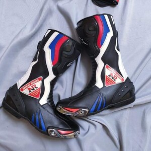 May include: A pair of black leather motorcycle boots with white, red, and blue accents. The boots have a  "MORRJAJ RACING" logo with the letters "NR" in a triangle.