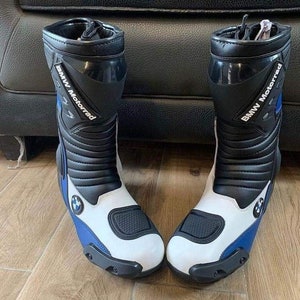 May include: A pair of black and white motorcycle boots with blue accents. The boots have the text "BMW Motorrad" on the side.