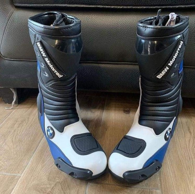 May include: A pair of black and white motorcycle boots with blue accents. The boots have the text "BMW Motorrad" on the side.