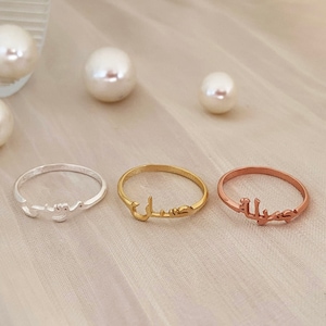 May include: Three rings with the Arabic word "Habibi" inscribed on them. The rings are made of silver, gold, and rose gold.
