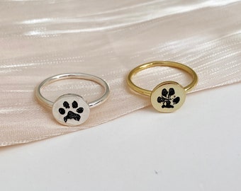 May include: Two rings with a paw print design. One ring is silver and the other is gold.