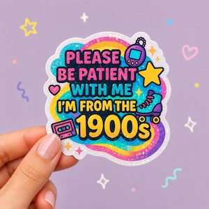 Könnte beinhalten: Ein farbenfroher Aufkleber mit dem Text "PLEASE BE PATIENT WITH ME I'M FROM THE 1900's". Der Aufkleber zeigt einen Regenbogen, eine Kassette, einen Rollschuh, einen Stern und ein Handheld-Spiel. Der Aufkleber wird von einer Hand gehalten.
