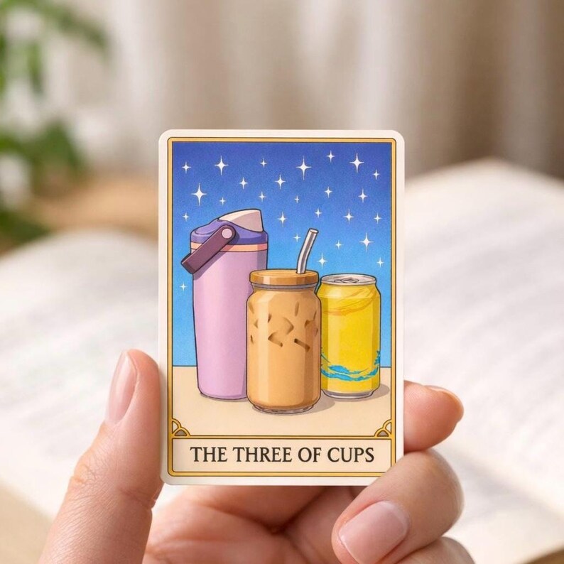 May include: A tarot card illustration featuring three beverages: a pink water bottle, a glass of iced coffee with a straw, and a yellow can. The background is a starry night sky. The text at the bottom reads "THE THREE OF CUPS."