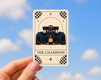 以下が含まれることがあります： 黒、赤、黄色のF1レーシングカーのデザインが施された長方形のステッカー。ステッカーはクリーム色の背景で、下部に「THE CHAMPION」の文字が入っています。車にはRed Bullのロゴが見えます。