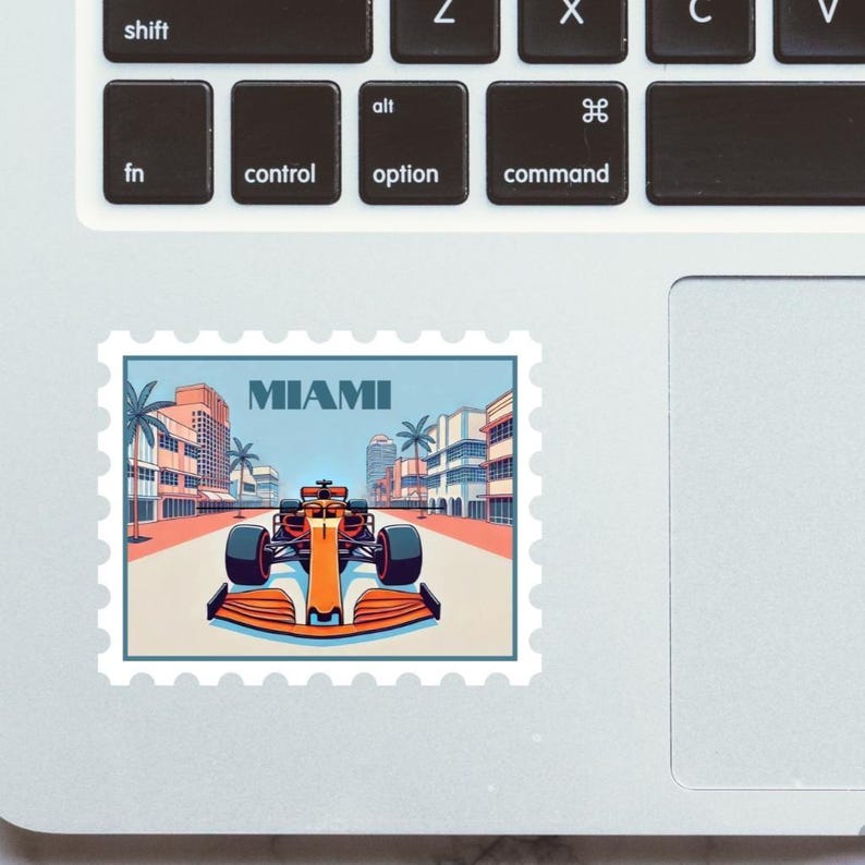 Lando Norris Mclaren F1 car racing in the Miami Grand Prix with art deco miami beach buildingsand MIAMI text with palm trees on a stamp sticker for sale on etsy on a laptop computer mockup marble table silver macbook