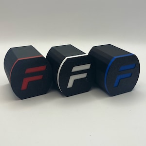 Könnte beinhalten: Drei schwarze achteckige Boxen mit weißem Rand und einem weißen, roten oder blauen Buchstaben "F" auf der Vorderseite.